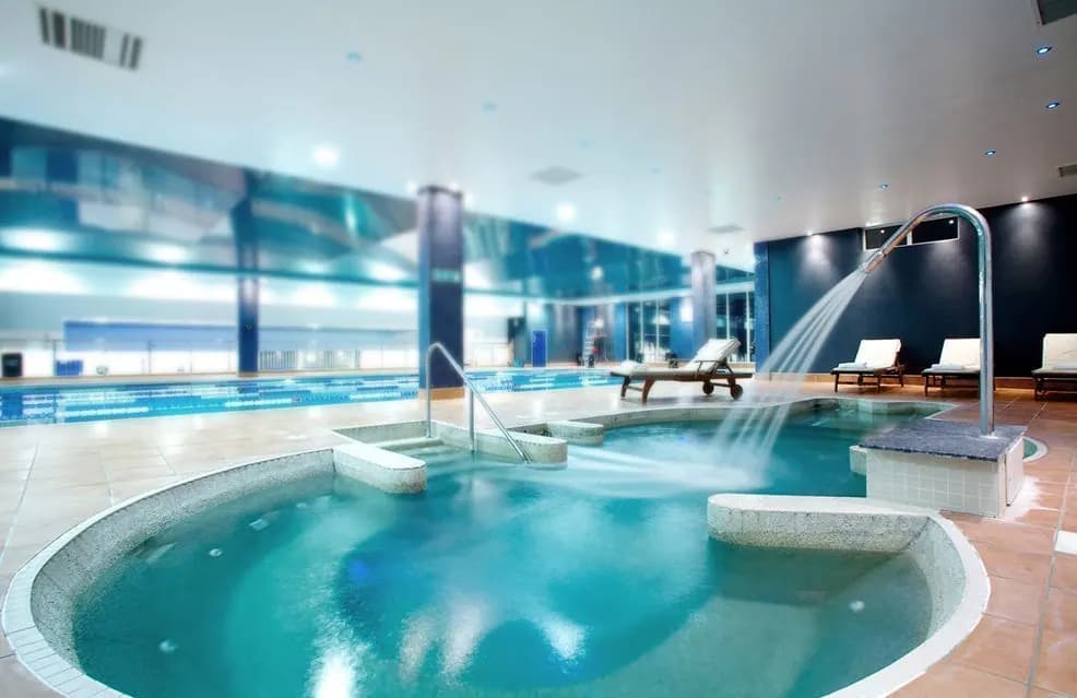 Spa interior con vaso de hidromasaje circular y ducha en cascada